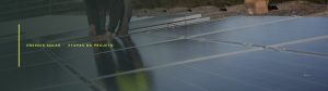 Instalador com capacete e colete fixando módulos fotovoltaicos em um telhado