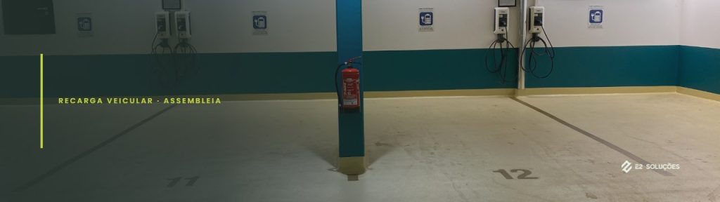 Quatro estações de recarga na parede de uma garagem de condomínio, com vagas numeradas