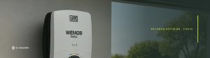 Estação de recarga WEMOB WALL da WEG instalada em parede, com o cabo ligado a um carro elétrico