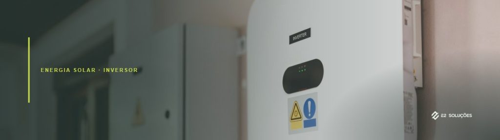 Inversor solar string instalado na parede externa de uma casa, com a string box ao lado e os cabos de conexão saindo por baixo